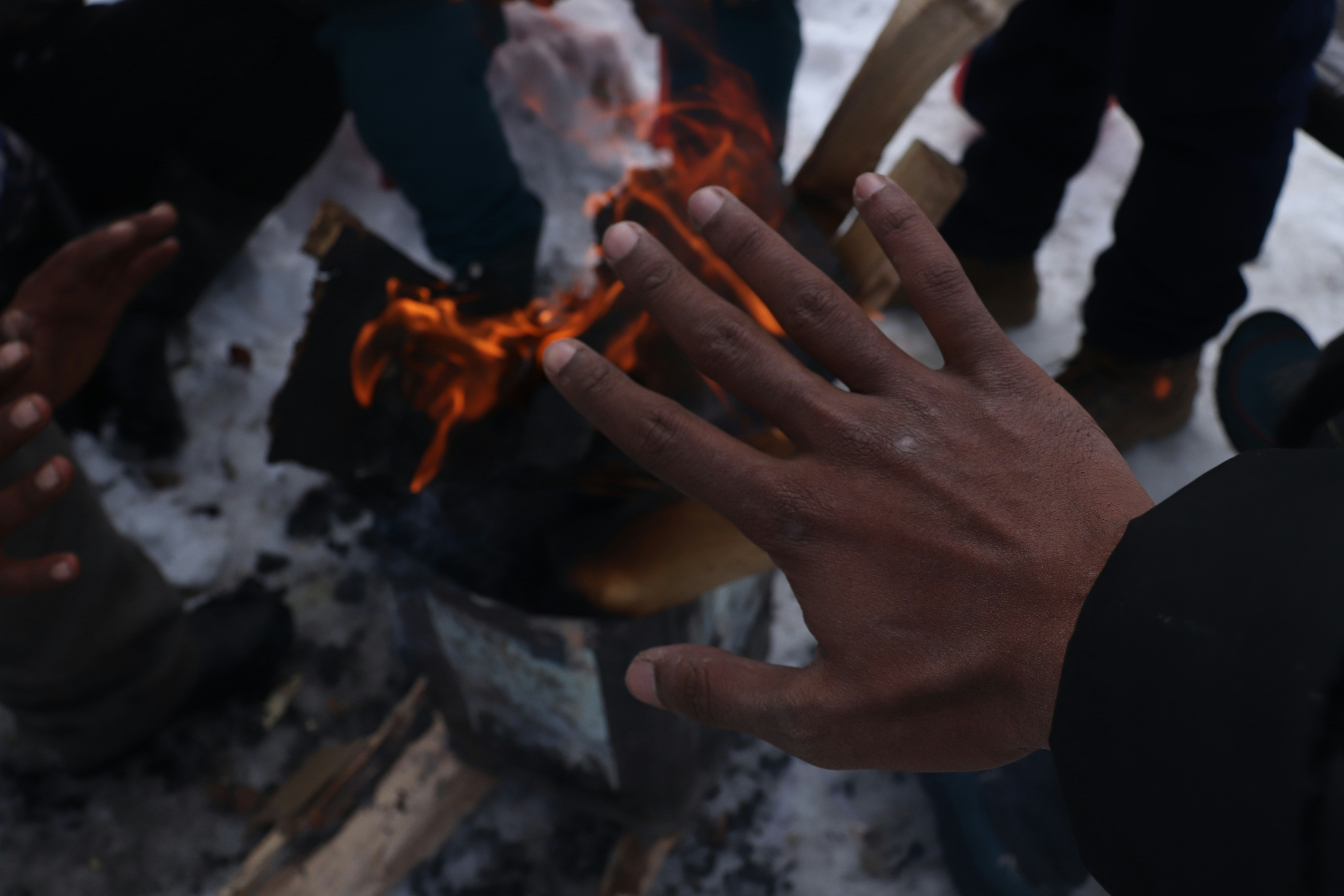 Hands coaxing a small fire from tinder